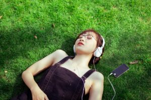 woman laying on the grass listening to music